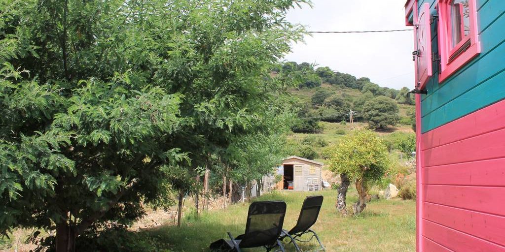 Chambres d'hotes U Cuventu di Paomia Cargese Corsica Frankrijk pipowagen roulotte tuin ligstoelen grasveld heuvels bomen